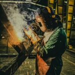 A skilled welder works on metal fabrication in a Brazilian factory, showcasing industrial precision.